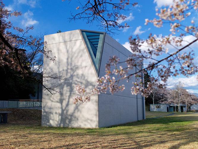 安藤忠雄の設計による〈光の美術館〉。コンクリートの箱の一角を切り欠いた、ストイックな建築。春になると樹齢を重ねた桜が咲き誇る。