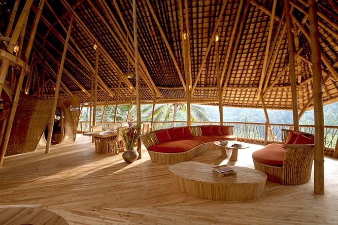 大きなソファとダイニングテーブルの置かれたラウンジスペース。家具や照明もイブクがこの建物に合わせ、竹を素材にしてデザインしたもの。外は野性味あふれる植物が囲み、ジャングルの中にいる気分。