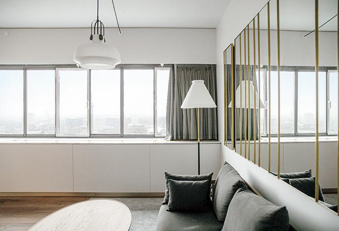 グレイッシュな家具とカーテンのシンプルな客室。風景を映す鏡がデコラティブな効果を発揮。