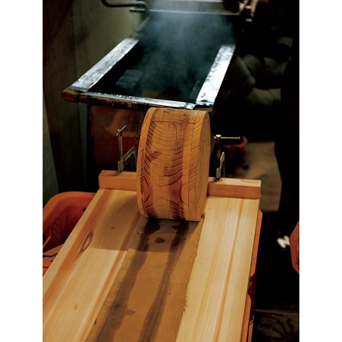 80℃の湯で煮た杉板を、ゴロ（丸太）に巻いて曲げる。