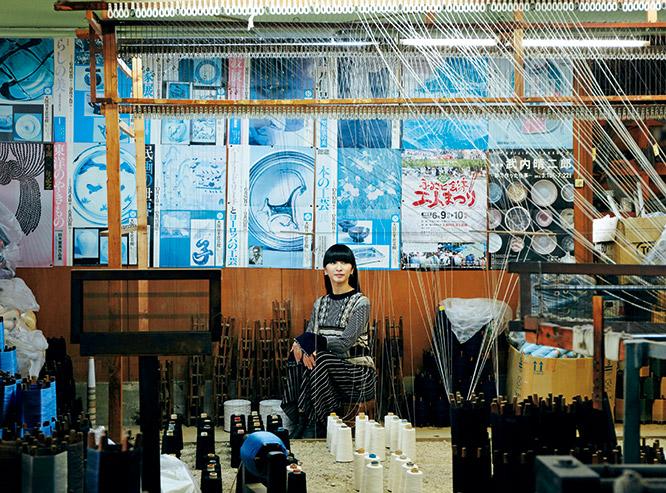 東北の伝統的な手仕事・刺し子を機械でつくる「刺し子織り」。その日本唯一の職人、大峡健市さんの工房で何千本もの糸を織機に掛ける光景に見とれるかしゆか店主。「まるでグランドピアノの中にいるみたいな気分です」
