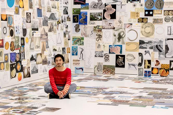 2018年、〈東京オペラシティ アートギャラリー〉で開催された際の展示風景。12のテーマでリサーチしたイメージが集まる最初の展示空間『記憶の発掘』に座る田根剛。photo_Satoshi Nagare