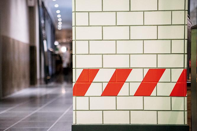 タイル壁にはNYの地下鉄で使われている立ち入り禁止区域を示す斜線を。深い赤は東急電鉄のコーポレートカラーへのオマージュ。