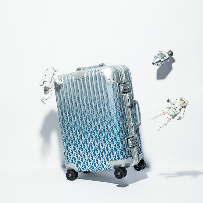 CABIN　1967年にマルク・ボアンが考案した、“ディオール オブリーク”柄で装飾された〈リモワ〉のアイコニックなスーツケース《キャビン》。“DIOR and RIMOWA”のシグネチャープレートも存在感あり。内部は、外装と同じ柄のライニングを採用し、荷物を仕切るフレックスディバイダーにもロゴ入りのバンドがデザインされるなど、随所に特別な仕様が。SIZE_H56×W40×D22cm　WEIGHT_4.3kg　PRICE_¥449,000／BLUE GRADATION　COLOR_BLUE GRADATION、BLACK、SILVER　BRAND_DIOR