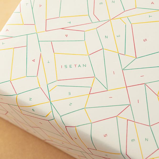 〈伊勢丹〉の新たな包装紙「radiance」。正方形をベースに、ポップな赤、黄、緑の線が交わって活き活きと伸びていくデザイン。線に囲まれたスペースには、「I・S・E・T・A・N」のアルファベットが散らばっている。