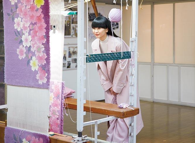 中国から織物の技術者を招き、靴を脱いで暮らす日本の絨毯として考案開発された「山形緞通」。小学校の校舎のような工房を訪ねたかしゆか店主は「色のグラデーションが綺麗。桜が立体的に見えるのもすごいですね」。