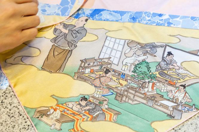 カレの裁断や縫製を行う工房の様子が描かれている、カレの部分アップ。机の上に描かれた猿（写真左下）は、日本では馬の守り神との説もある。　photo_Manami Takahashi