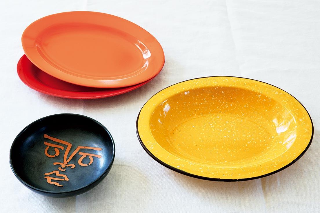 “旅”というテーマで選んでもらった3枚。右／黄色いホーローの深皿はメキシコの蚤の市で。「さらっと盛り付けてもさまになるオーバル皿が大好き。麺類にも合うちょうどいい深さで、活躍度はナンバーワン」。28×23×D3.5cm。左上／メラミン製のオーバル皿は、クアラルンプールで発見。「焼きそばや和え麺をのせると最高。ゆでたアスパラをそのまま並べても」。左下／南仏のピカソ美術館で購入。「ヨーグルトにぴったり。食べ進めるとピカソが描いた顔の絵が現れます」