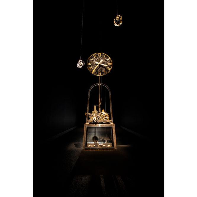 アンティーク時計の針が逆行するように歯車を改変した杉本博司の作品《逆行時計》。光学ガラスの錘がゆっくりと下降するにつれて針が逆回りする。