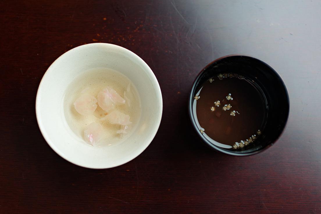 薄く塩味がついている「【突き出し】桜茶」は見た目も美しい。ひと口サイズの「おぜんざい」は香ばしいあられ入り。夏は冷やしバージョンに。