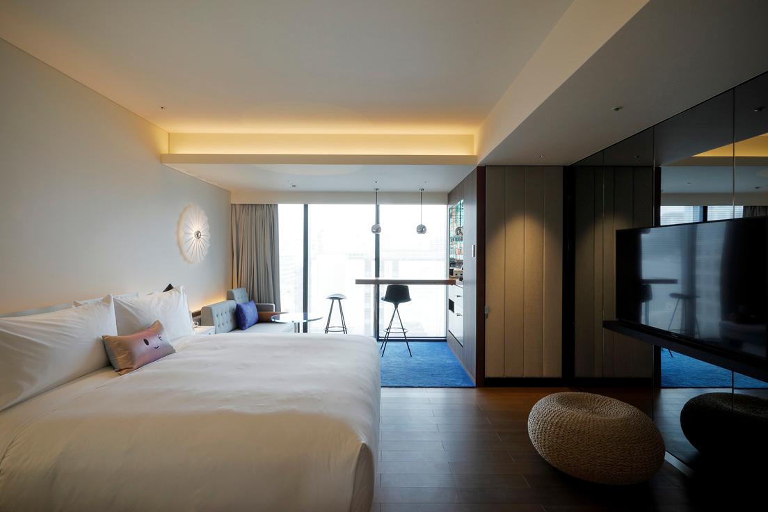 スタンダードルーム・コージーの客室。ベッドは世界中の〈Wホテル〉で採用されているシグネチャーベッド。日本のKawaii文化にインスピレーションを受けたオリジナルクッションも見える。