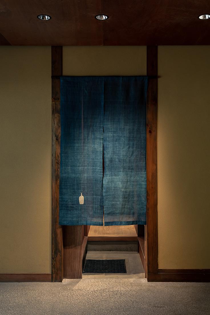 予約時間になると担当のバリスタが迎えに現れる。徳島の藍染ブランド〈BUAISOU〉がロゴマークを染め抜いた暖簾をくぐり2階へ。