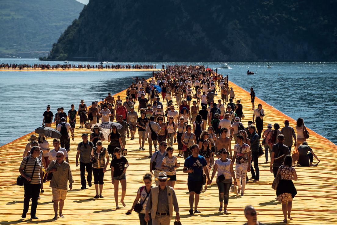オレンジの桟橋を架け湖上を人々が歩ける《フローティング・ピアーズ》（2014-16）。イタリアで開催。クリスト生前最後のプロジェクトとなった。The Floating Piers Lake Iseo, Italy, 2014-16 / Christo and Jeanne-Claude, Photo: Wolfgang Volz