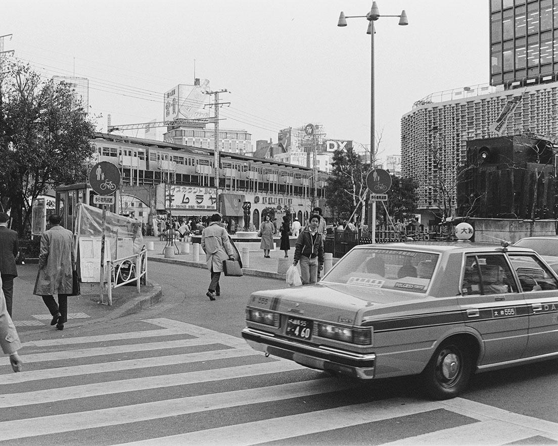 《新橋駅前SL広場1984》1966年、駅をはさんだ汐留口に〈新橋駅前ビル〉が開業、71年日比谷口に〈ニュー新橋ビル〉がオープン。翌72年、駅前広場が整備されC11形蒸気機関車が動態保存された。