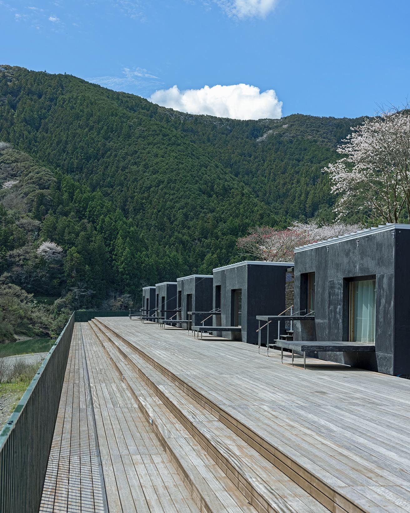 隈研吾とスノーピークが共同開発したモバイルハウス〈住箱-JYUBAKO-〉が、ウッドデッキに10棟並ぶ。photo_Norio Kidera