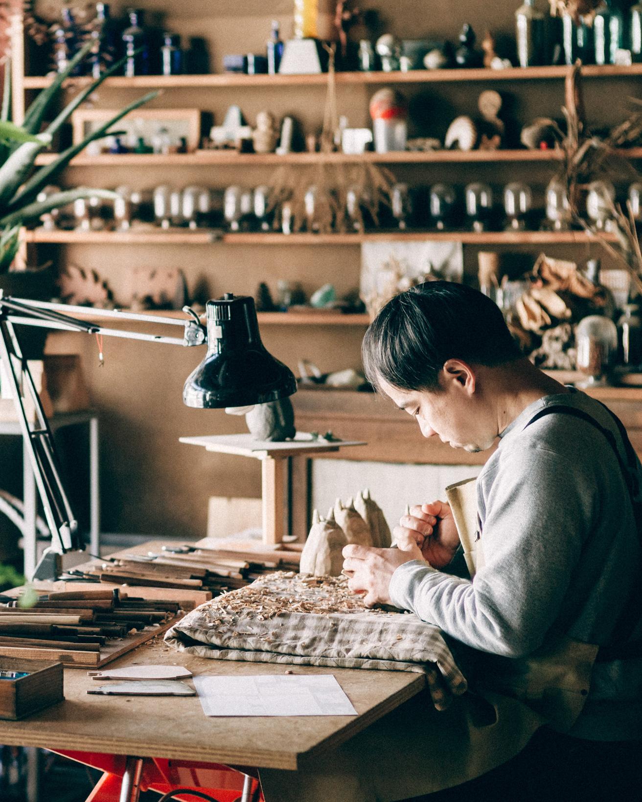 井波彫刻、木彫と漆の工房『トモル工房』で木彫りのトトロを制作中の田中孝明さん。 