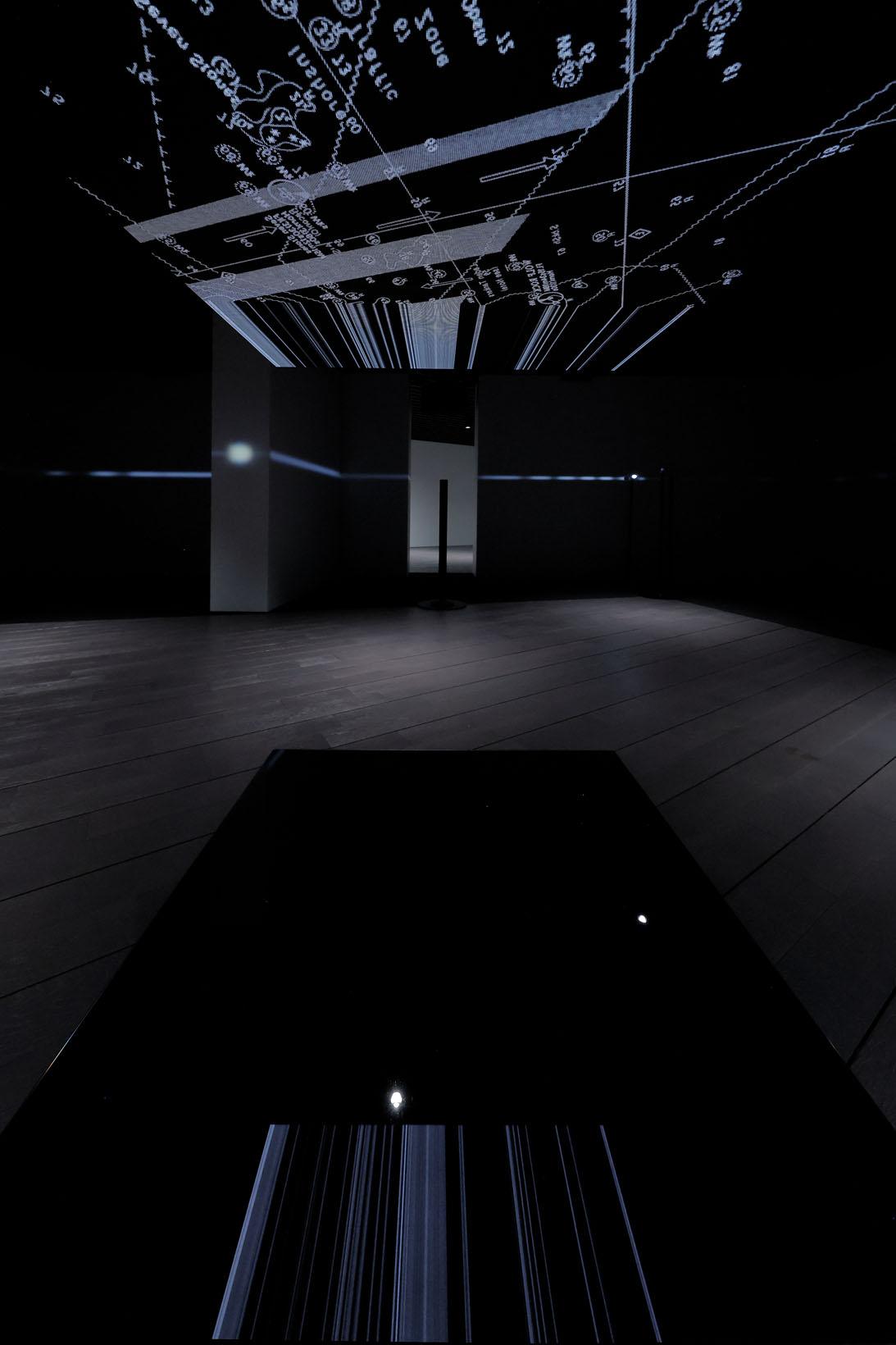 頭上のビデオパネルの画像が床の黒い鏡に映し出される。