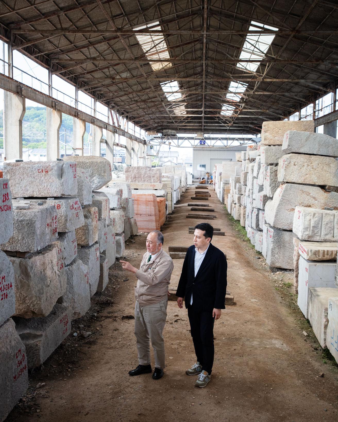 国内外の石材を扱う老舗〈矢橋大理石〉を訪ね、代表取締役社長・矢橋修太郎氏とヤードを歩く榊田倫之（右）。photo_Yuji Ono