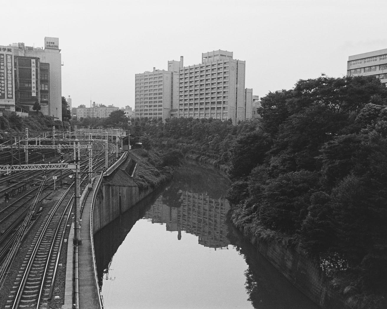 《御茶ノ水・神田川1984》お茶の水橋から神田川、水道橋駅方面を望む。大きな建物は順天堂大学。