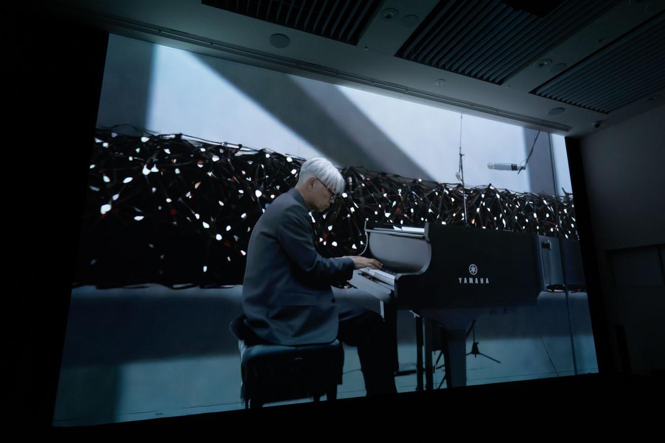 真鍋大度＋ライゾマティクス＋カイル・マクドナルド《Generative MV》（2023年）。観客が入力したテキストに応じてAIがリアルタイムで背景を描く。