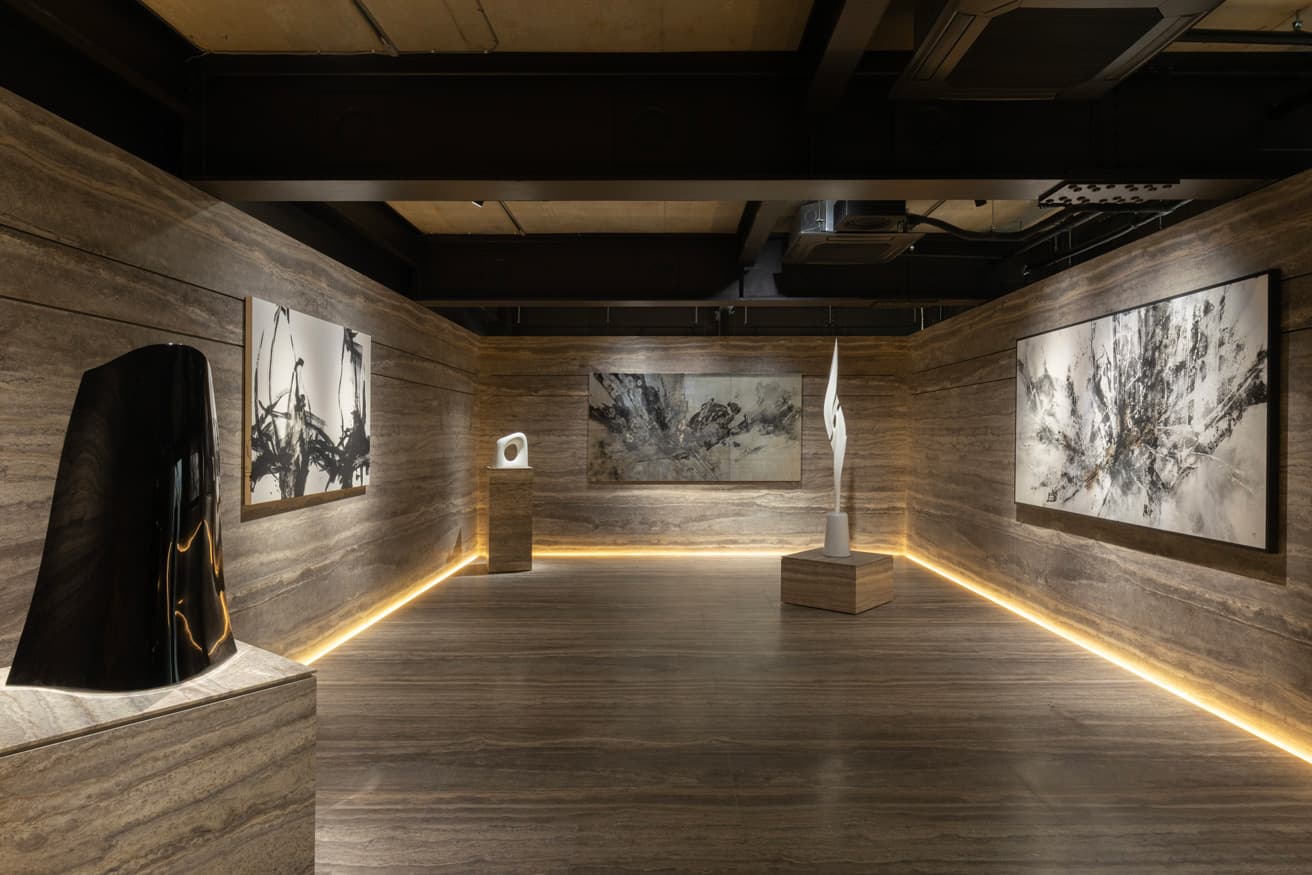 1階展示スペース。イタリア産トラバーチンを貼った壁と床が接する部分にライトを入れた雰囲気ある空間づくり。作品を個別に浮かび上がらせる照明設計も完璧。