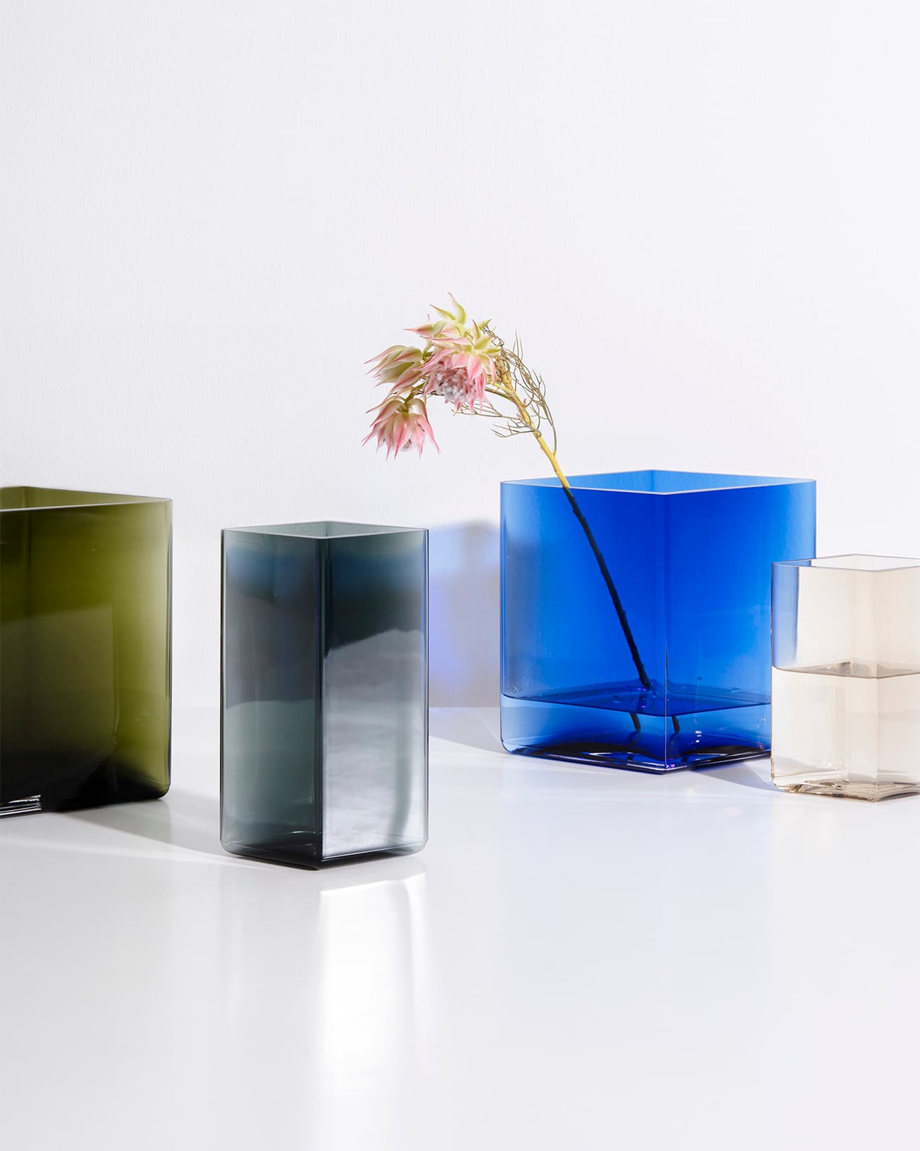 直線のみで構成された形、あえて不完全な色のグラデーションが織りなす《ルーツ》は水面や活けた植物のラインまでも引き立てる。左から/《ルーツ ベース》モスグリーン 205×180mm 33,000円、グレー 115×180mm 25,300円、リネン 115×140mm 16,500円。他に陶器のタイプもある。